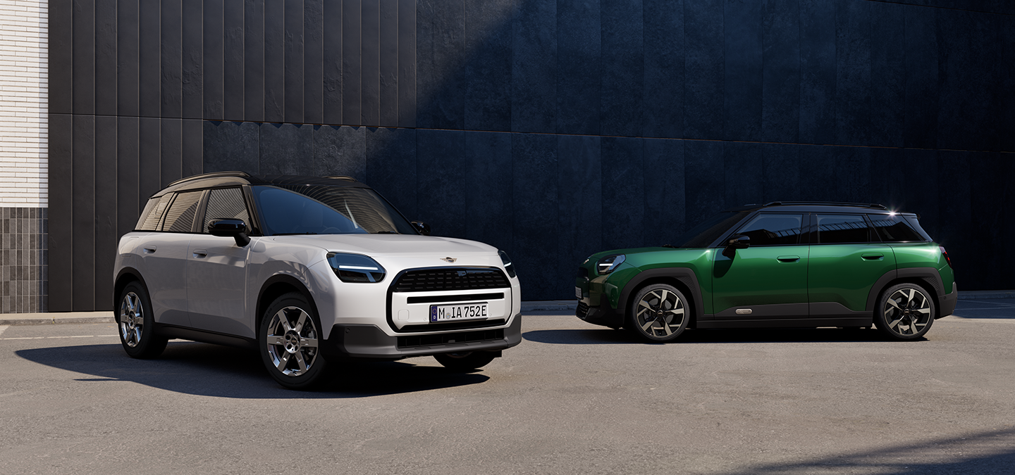 Voor- en zijaanzicht van de MINI Aceman Electric in Nanuq White en British Racing Green met Black Roof op een straat.