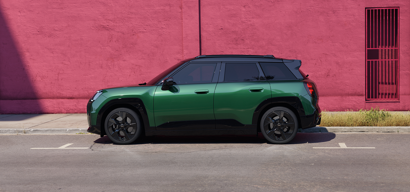 Zijaanzicht van de MINI Aceman Electric in British Racing Green en Black Roof op een straat.