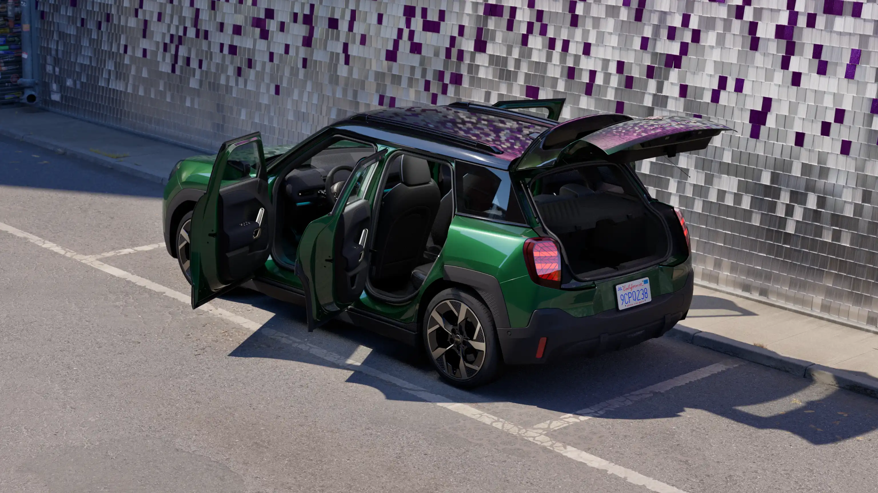 Achterkant van een MINI Aceman Electric in British Racing Green op een parkeerplaats met alle deuren open en een gekleurde muur op de achtergrond