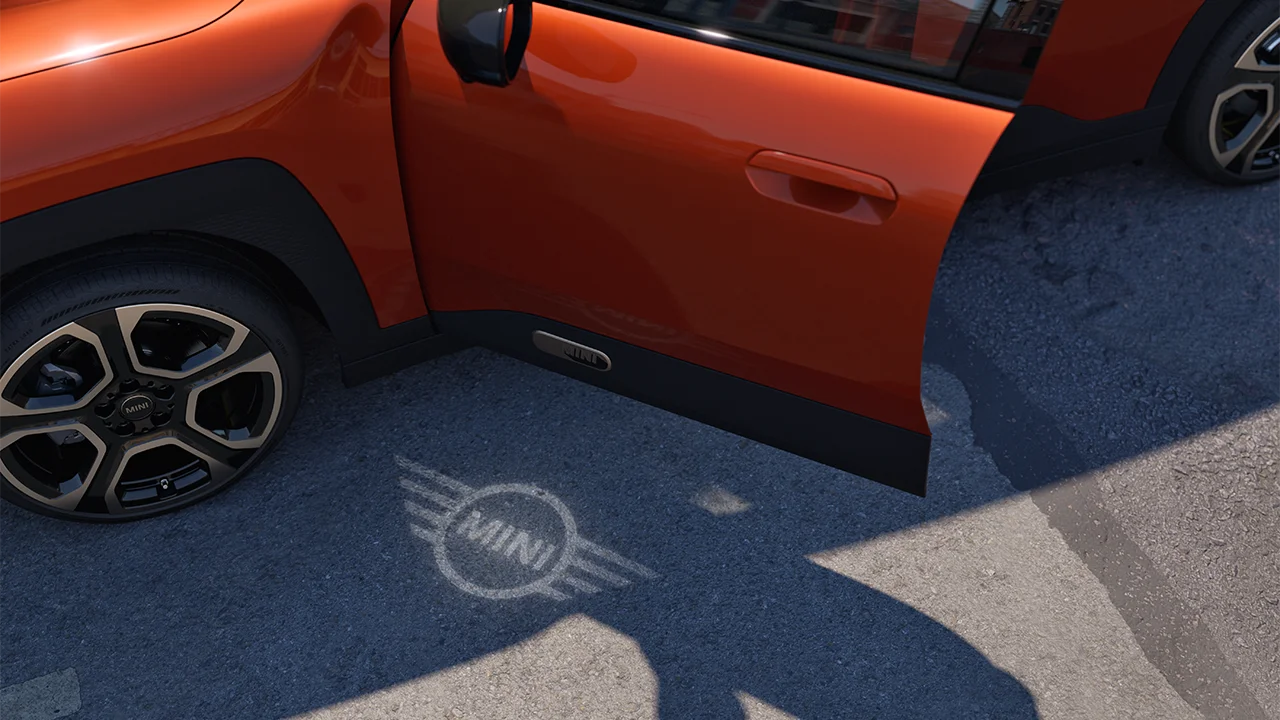 Buitenkant van de MINI Aceman Electric met open deur en het MINI logo als welkomstlicht op de grond