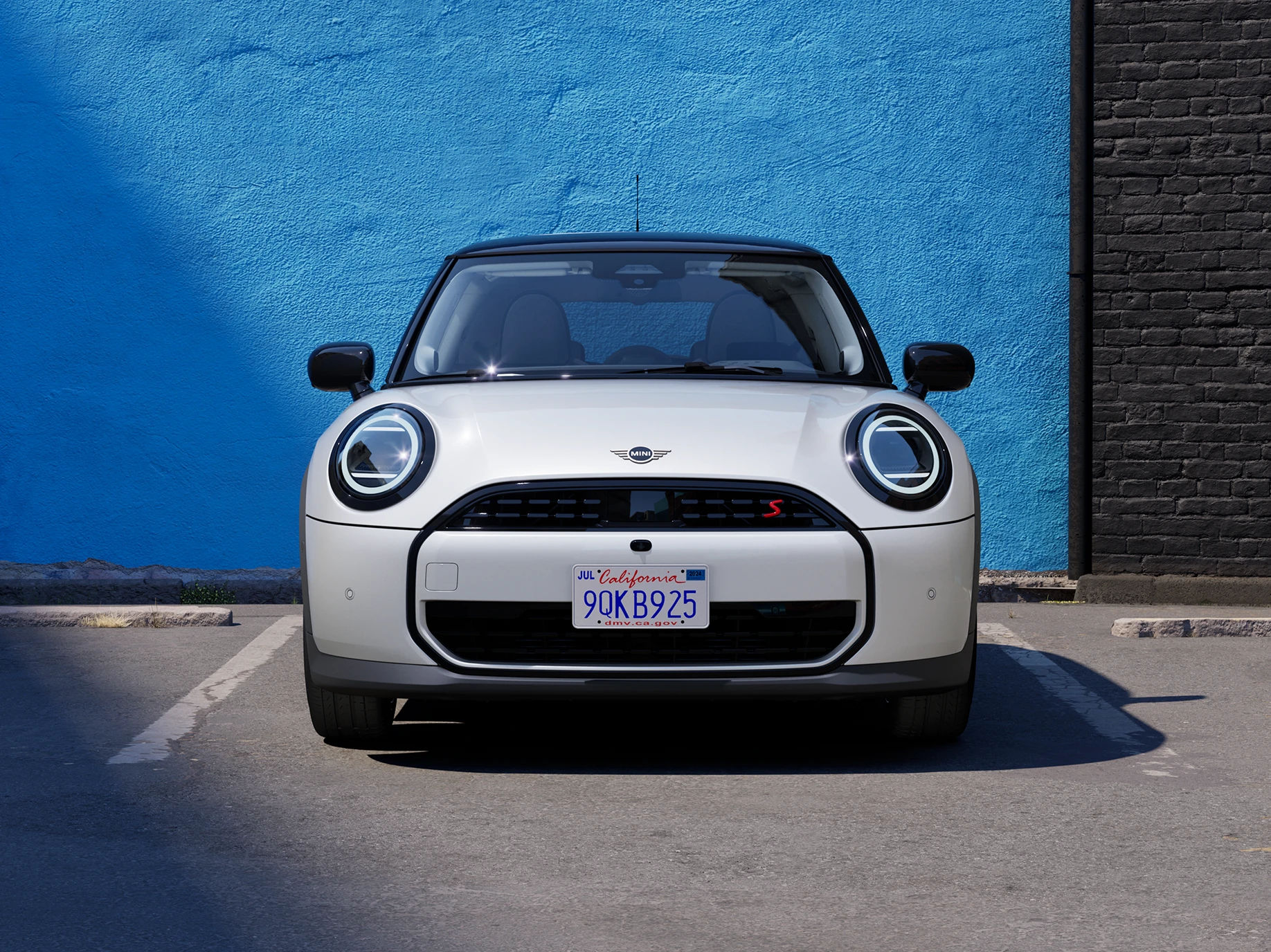Vooraanzicht van de MINI Cooper in Nanuq White met Black Roof op een parking.