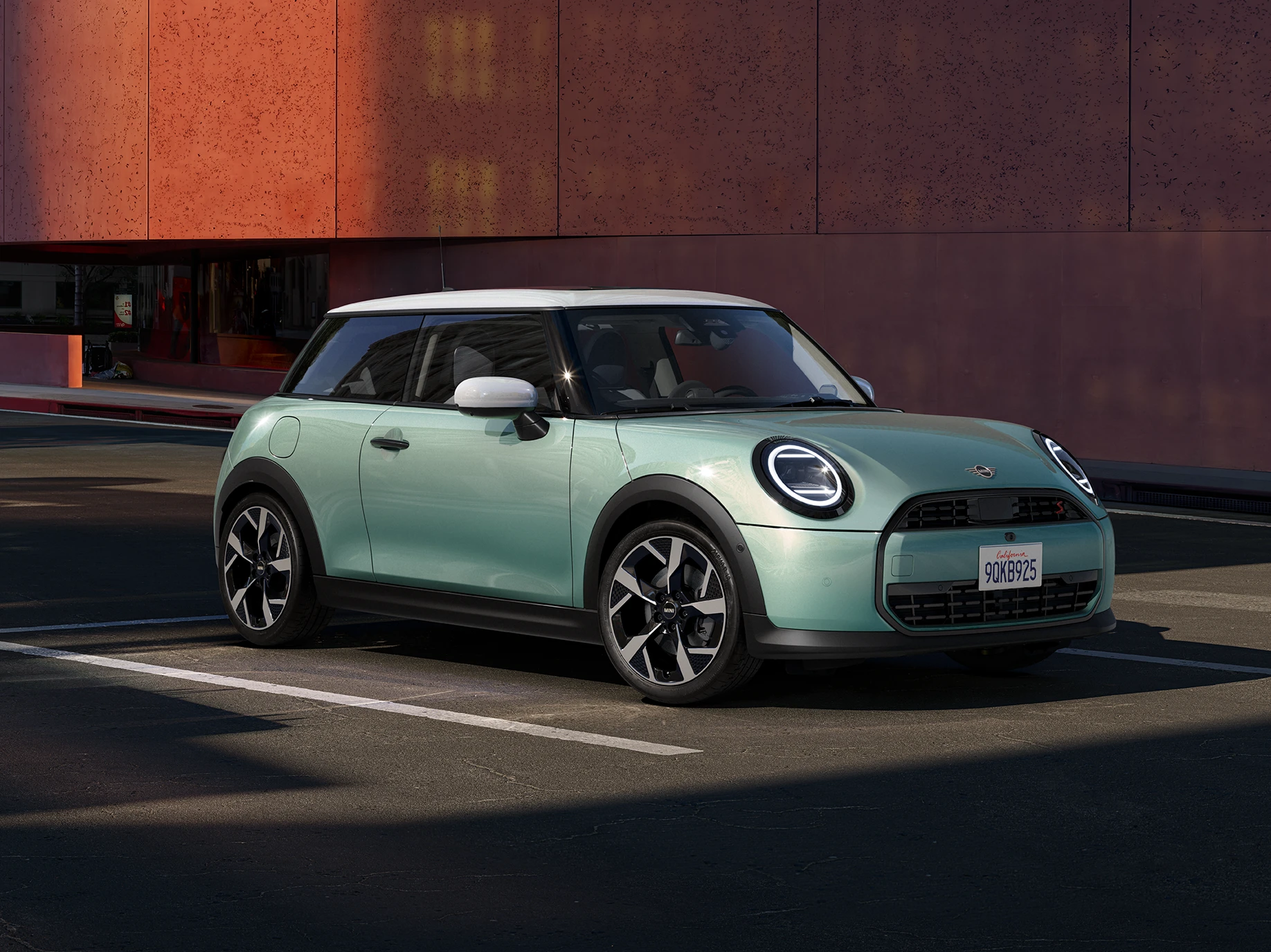 Zijaanzicht van de MINI Cooper in Ocean Wave Green en White Roof.
