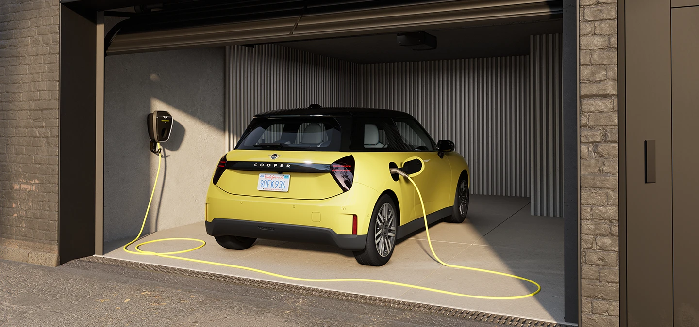 Achteraanzicht van een MINI Cooper Electric in Sunnyside Yellow tijdens het opladen in een garage. 