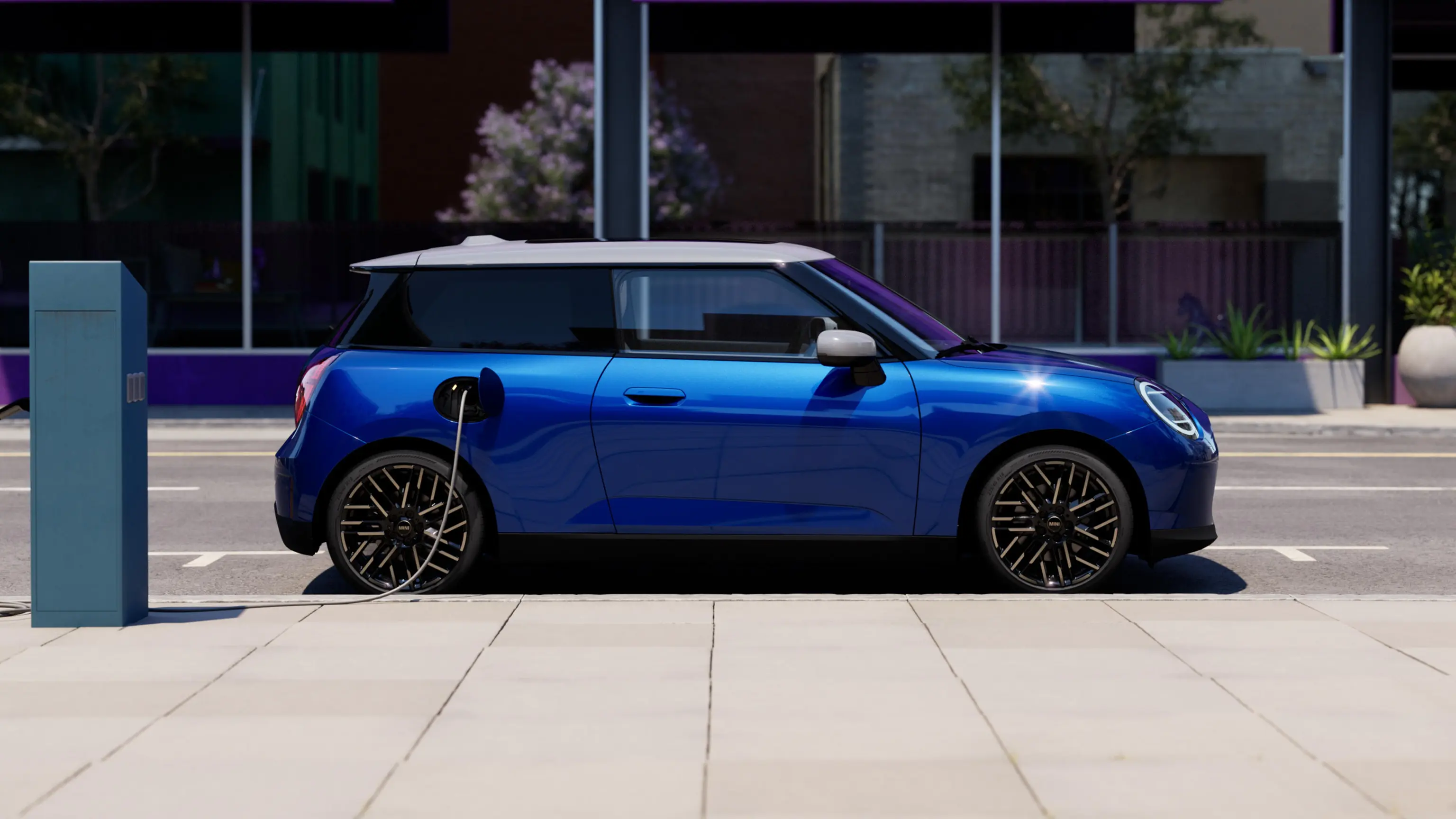 Vue latérale de la MINI Cooper Blazing Blue 100% électrique garée à côté d'une borne de recharge