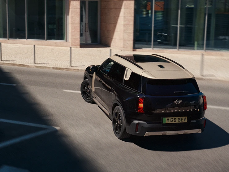 Vue du dessus arrière de la MINI Countryman Electric Midnight Black avec toit Vibrant Silver en stationnement,