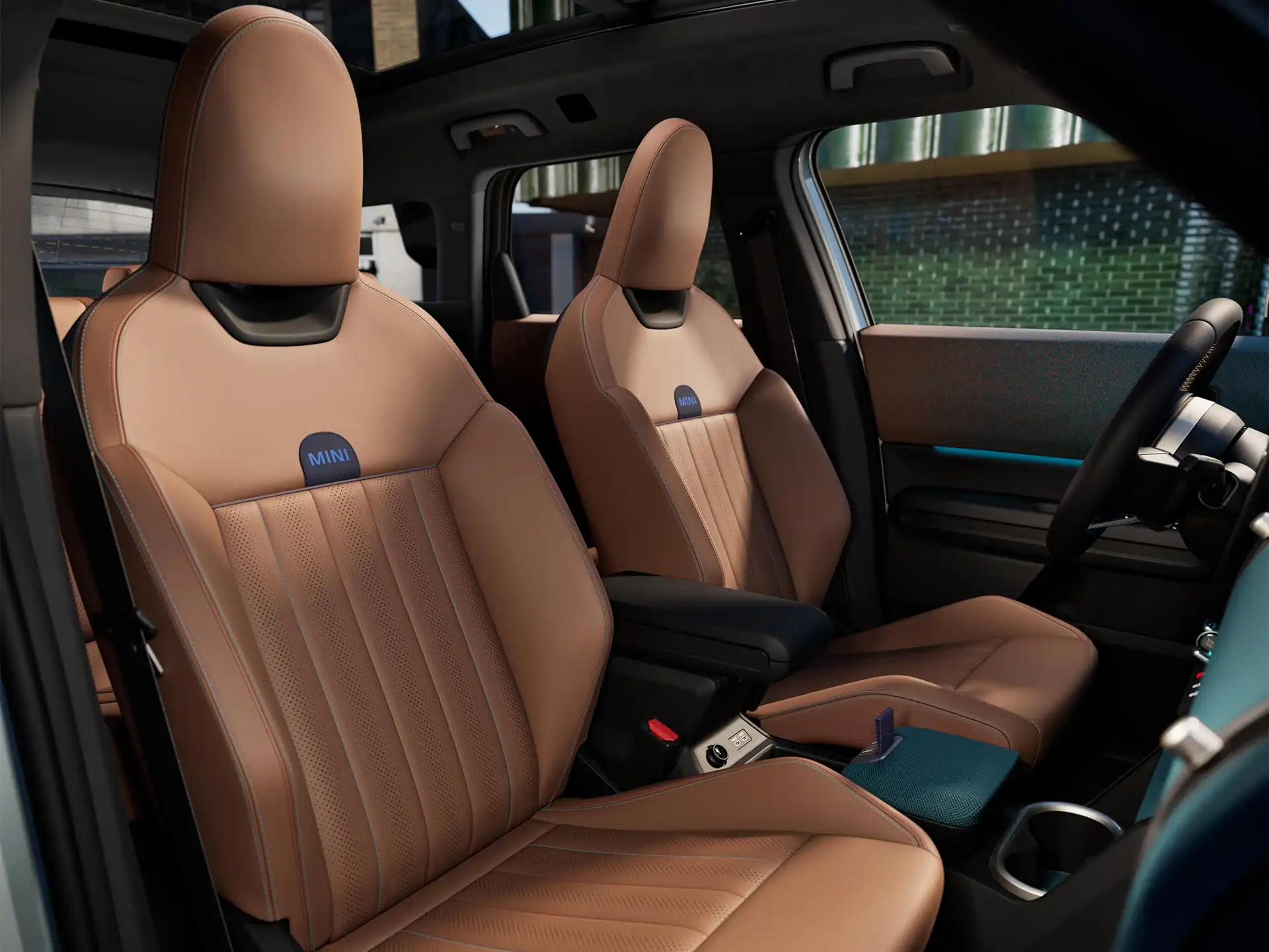 Vue intérieure de la MINI Countryman 100 % électrique montrant le tableau de bord, le volant, l’écran rond, le toit panoramique en verre et l’arrière des sièges avant.