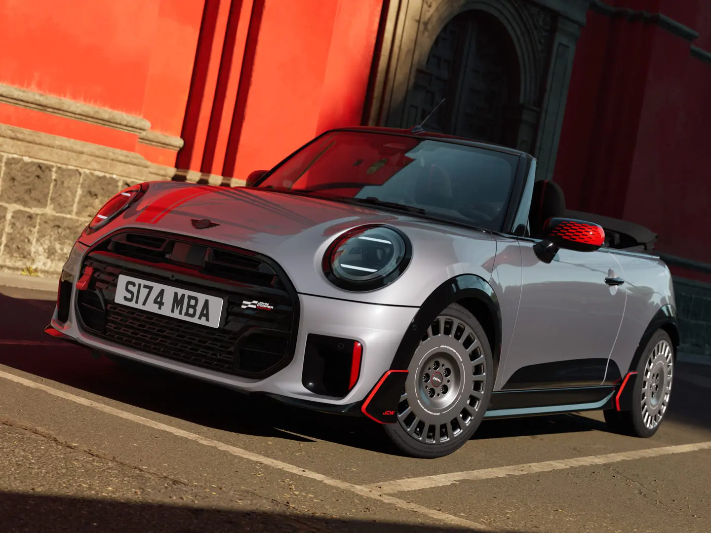MINI Cabrio en Silver arborant des produits décoratifs et sportifs JCW, notamment des coques de rétroviseurs, des bandes sport et une ailette MINI JCW.