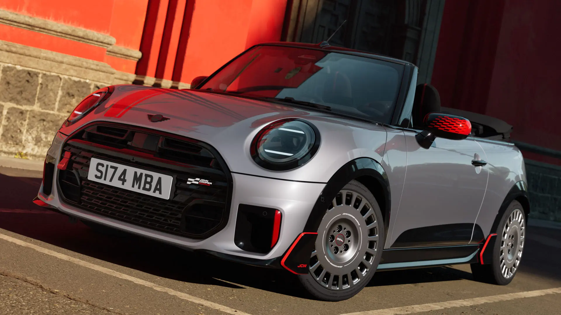 MINI Cabrio en Silver arborant des produits décoratifs et sportifs JCW, notamment des coques de rétroviseurs, des bandes sport et une ailette MINI JCW.