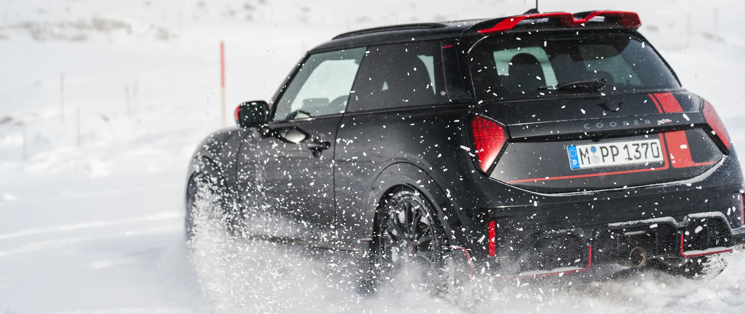 Vue arrière d'une MINI Cooper JCW roulant dans la neige.