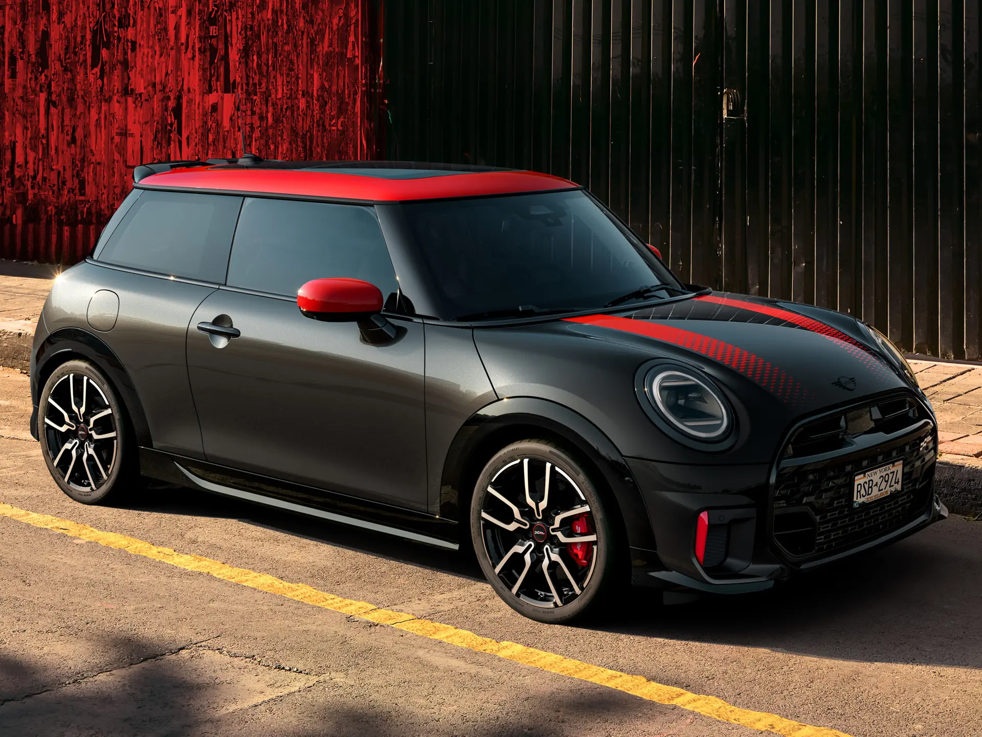 MINI John Cooper Works 3 portes Midnight Black avec toit et coques de rétroviseurs en Chili Red et bandes sportives rouges, vue latérale, garée dans la rue.