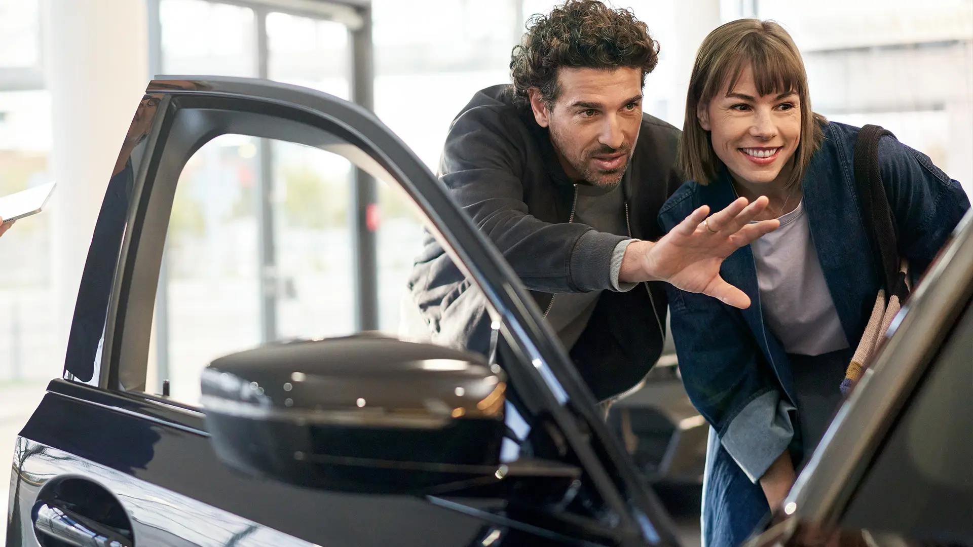 MINI stationnée à l’intérieur d’une concession MINI, avec un conseiller qui explique les caractéristiques intérieures à un client.