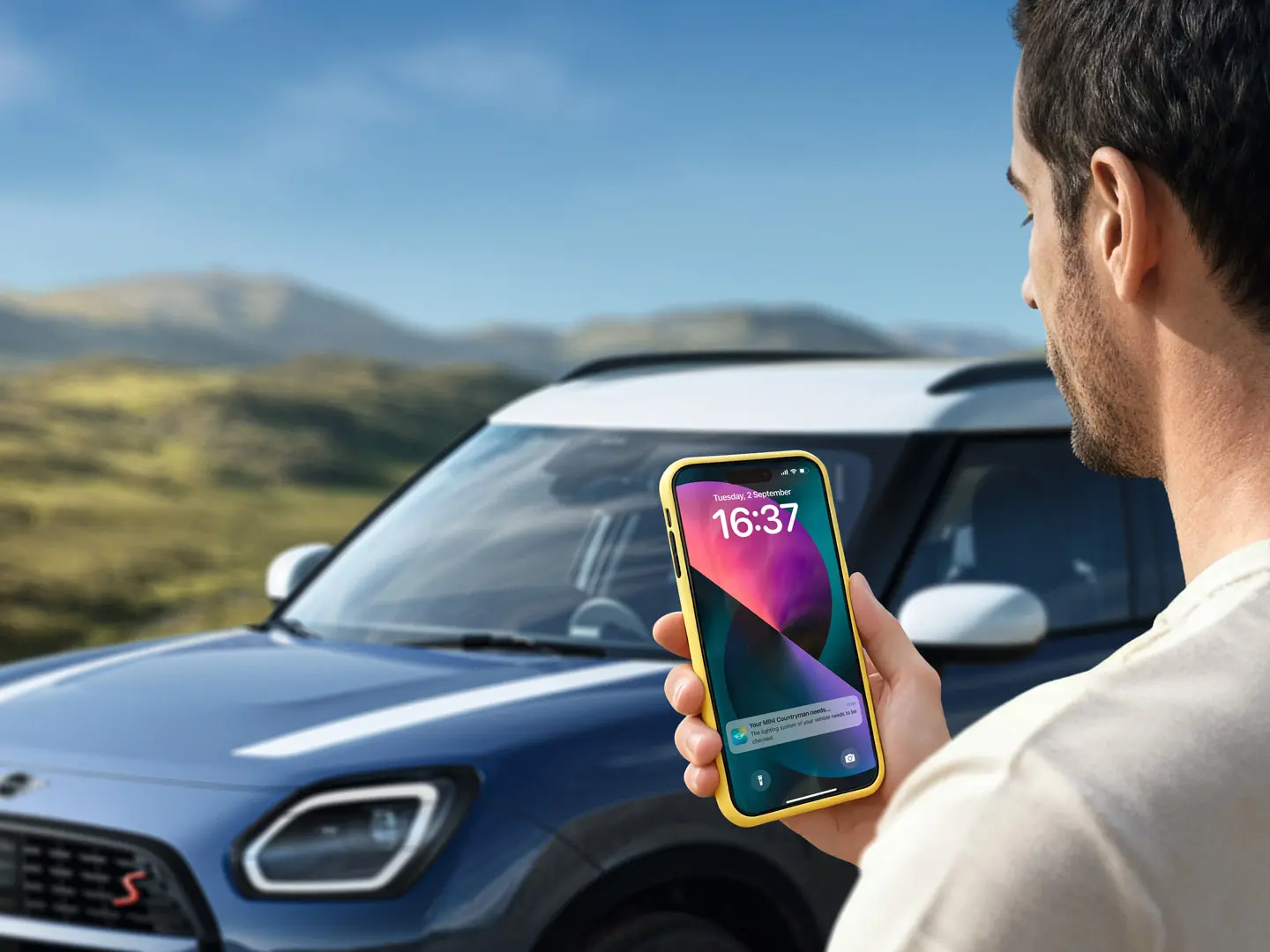 Un conducteur de MINI Countryman en train d’utiliser la MINI App pour contacter le service MINI Roadside Assistance. 