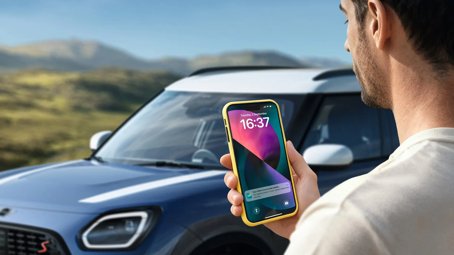 Un conducteur de MINI Countryman en train d’utiliser la MINI App pour contacter le service MINI Roadside Assistance. 