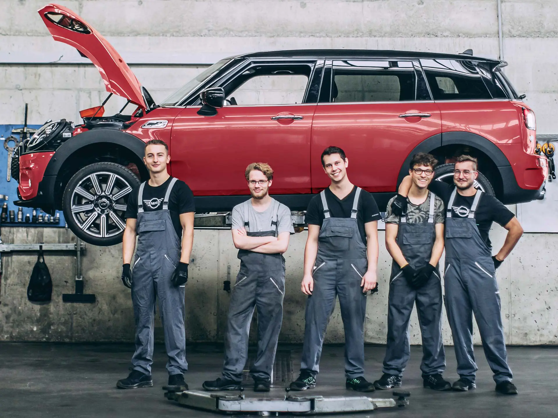 Des employés MINI devant une MINI Countryman sur un pont élévateur.