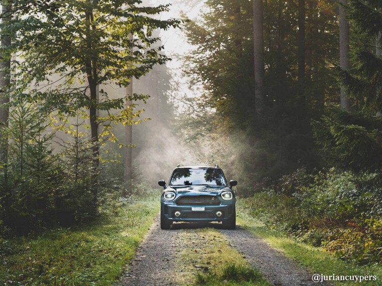 MINI Cooper rijdt over een verlaten bospad.